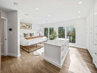 Experience modern luxury in this spacious bedroom featuring a king-size bed, a sleek white island, and ample storage with built-in closets.