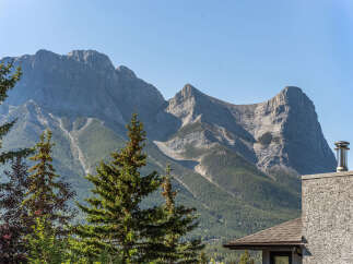 Experience breathtaking mountain views from this stunning property, nestled amidst lush greenery and towering trees.