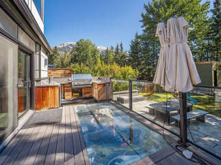 Experience luxury outdoor living with this stunning deck featuring a built-in grill station and a unique glass-covered feature.
