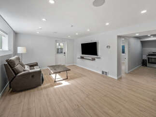Experience modern living in this beautifully renovated space featuring a comfortable recliner sofa and a sleek wall-mounted TV, perfect for entertainment.