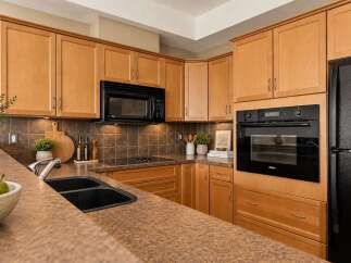Discover this beautifully appointed kitchen featuring warm, natural wood cabinetry that complements the rich, tiled backsplash.