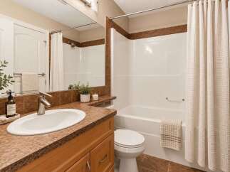 This bright and clean bathroom features a spacious vanity with a granite countertop and an undermount sink, complemented by a large mirror and ample lighting.