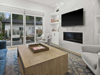 Experience modern living in this stunning living room, featuring a sleek fireplace with a marble surround and a wall-mounted TV.