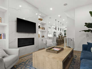 Experience modern living in this stunning open-concept space, featuring a sleek fireplace with a marble accent wall and a wall-mounted TV.