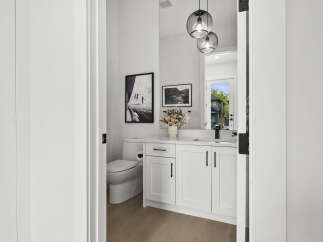Step into this stylish powder room featuring a modern white vanity with sleek black hardware and a marble countertop.
