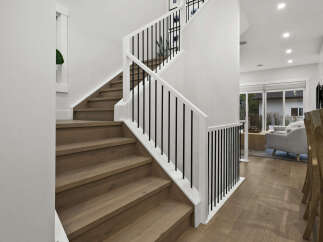This modern staircase features sleek white railings with black vertical balusters, complementing the warm, natural wood treads.