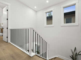 Step into this bright and airy hallway, featuring a modern staircase with sleek black balusters and a crisp white railing.