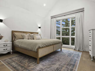 Experience serene living in this beautifully appointed bedroom, featuring a luxurious bed with plush pillows and a stylish cane headboard.