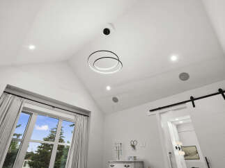 Experience modern luxury in this stunning bedroom featuring a vaulted ceiling with a contemporary circular chandelier and recessed lighting.