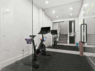 This modern home gym features a Peloton bike and dumbbells, perfect for your fitness routine.