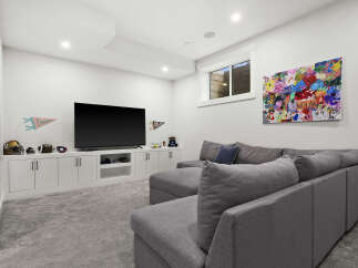 This modern basement living area features a large, comfortable sectional sofa perfect for family movie nights.