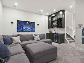 Experience ultimate relaxation in this modern basement living area, featuring a spacious sectional sofa perfect for movie nights.