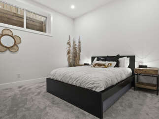 This modern bedroom features a stylish black platform bed with a textured white duvet and decorative pillows, creating a cozy and inviting atmosphere.