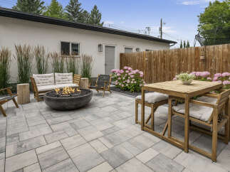 Enjoy outdoor living with this beautifully designed patio featuring a modern fire pit and comfortable seating.