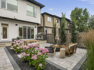 Experience outdoor living at its finest in this beautifully landscaped backyard, featuring a modern patio with a built-in grill and a cozy fire pit area.