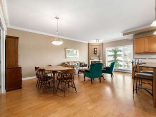 This spacious open-concept living area features a cozy dining nook with a round wooden table and chairs, perfect for family meals.