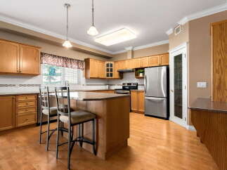 This spacious kitchen features warm oak cabinetry and a large central island, perfect for meal preparation and casual dining.