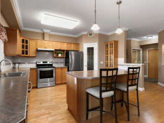 This spacious kitchen features warm oak cabinetry, a stainless steel refrigerator, and a convenient island with bar seating.