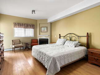 Experience comfort and elegance in this charming bedroom, featuring a cozy fireplace and a spacious bed with plush pillows.