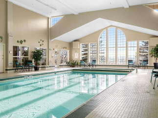 Indulge in relaxation at this stunning indoor swimming pool, featuring a spacious design and abundant natural light pouring in from the large arched windows.