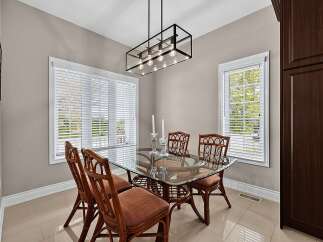 This dining room features a sleek glass-top dining table with four rattan chairs, perfect for intimate gatherings.