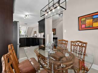 Experience elegant dining in this beautifully appointed space, featuring a sleek glass-top dining table with rattan chairs, perfect for intimate gatherings.