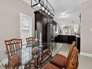Enjoy elegant dining in this bright space, featuring a sleek glass-top table with comfortable rattan chairs.