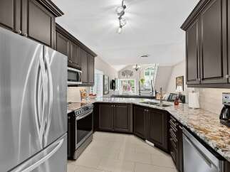 This spacious kitchen boasts dark espresso cabinetry complemented by stunning granite countertops and a classic subway tile backsplash.