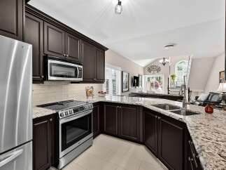 Experience culinary excellence in this stunning kitchen, featuring rich espresso cabinetry and gleaming granite countertops.