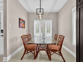 This dining room features a stylish glass-top dining table with rattan chairs, perfect for intimate gatherings.