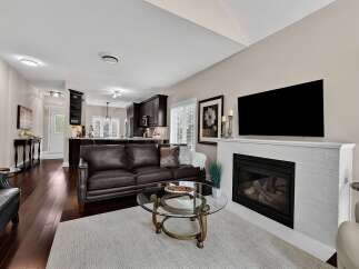 Experience modern living in this beautifully appointed open-concept home, featuring a spacious living area with a cozy fireplace and a sleek, dark-wood kitchen perfect for entertaining.