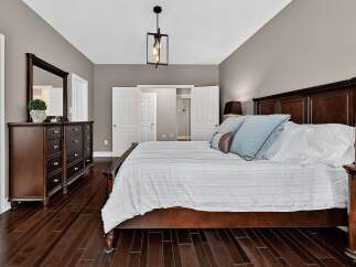 Experience luxury in this master bedroom, featuring a grand dark wood bed with plush blue and brown accent pillows.
