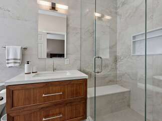 Experience modern luxury in this stunning bathroom, featuring a sleek vanity with ample storage and a pristine white countertop.