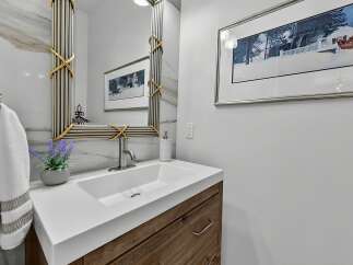 This modern bathroom features a sleek white vanity with a wooden base, complemented by a minimalist white sink and brushed nickel faucet.