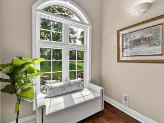 Bathed in natural light, this charming nook features a large arched window overlooking a lush green yard.