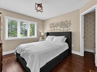 Discover comfort and style in this inviting bedroom, featuring a plush king-sized bed with crisp white linens and a striking metal tree wall art above.