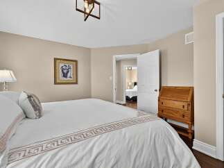 This bedroom features a comfortable queen-sized bed with elegant white bedding adorned with a Greek key pattern.