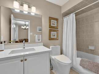 This bright and airy bathroom features a spacious vanity with a white quartz countertop and elegant gold hardware.