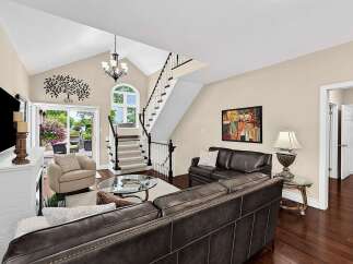 Step into this stunning living room featuring a vaulted ceiling and a grand staircase.