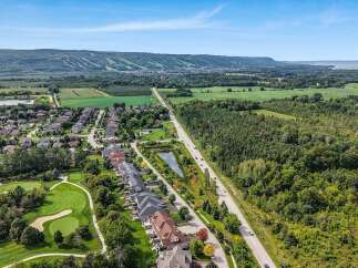 Discover this stunning aerial view showcasing a picturesque suburban neighborhood nestled beside a lush golf course and a serene pond.