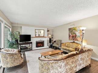 Step into this charming living room featuring a cozy fireplace and elegant floral-patterned seating.