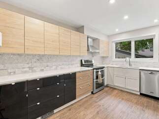 Experience modern living in this stunning kitchen, featuring sleek cabinetry in a mix of natural wood and high-gloss black finishes.