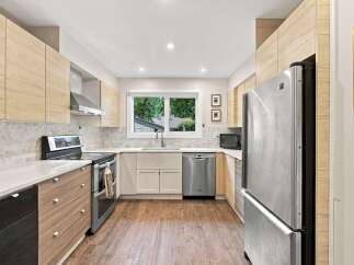 Experience modern living in this stunning kitchen, featuring sleek, light wood cabinetry and a striking marble herringbone backsplash.