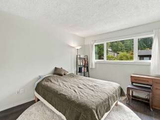 Discover comfort and style in this charming bedroom, featuring a cozy bed adorned with a textured quilt and plush pillows.