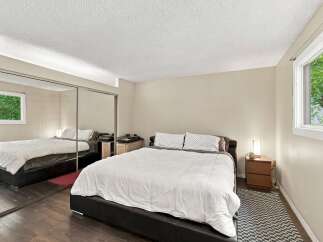 This spacious bedroom features a large, comfortable bed with crisp white linens, complemented by stylish patterned pillows.
