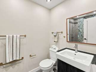 This modern bathroom features a sleek white sink with a brushed brass faucet, complemented by a dark wood vanity.