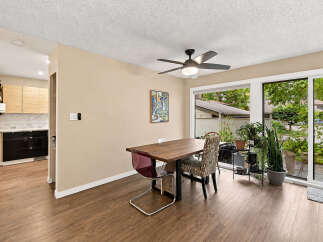 Enjoy meals in this bright dining area featuring a modern wooden table and chairs, complemented by a large sliding glass door that floods the space with natural light.