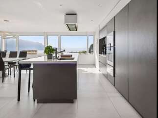 Experience modern luxury in this stunning kitchen featuring a sleek island with integrated lighting and a breathtaking panoramic view of the lake and mountains.