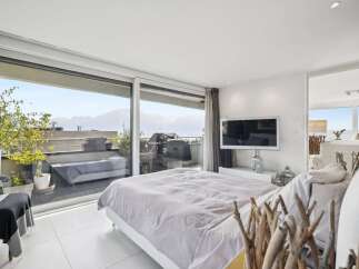 Experience luxurious living in this stunning bedroom featuring a large sliding glass door that opens to a private balcony with breathtaking mountain and lake views.