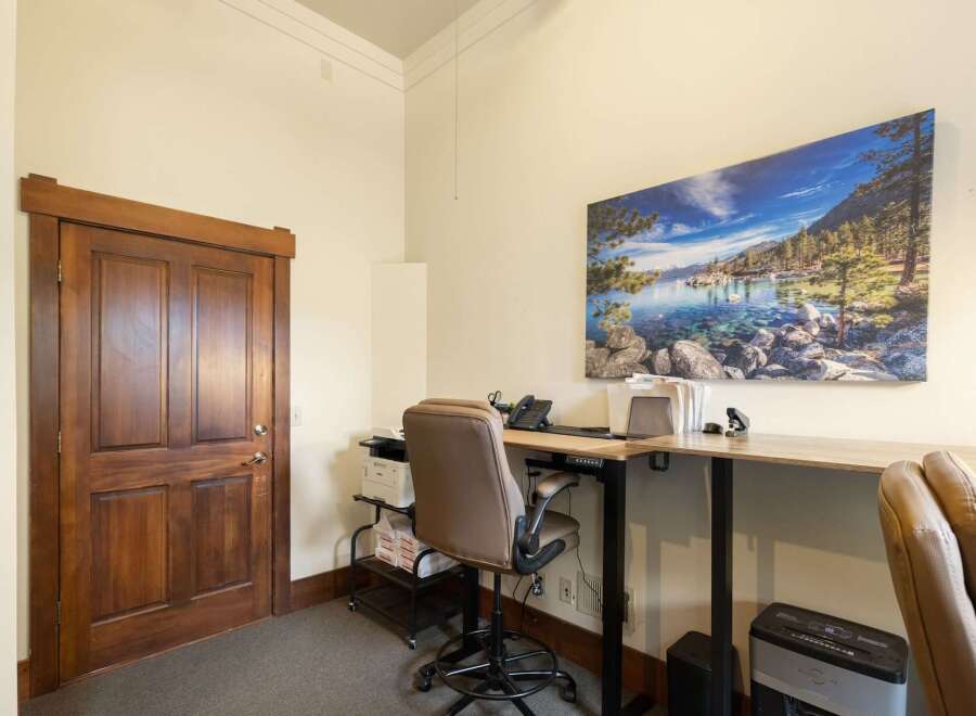 This office space features a beautiful wooden door and a large, scenic wall art that adds a touch of nature to the room.